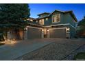 Three-car garage with an expansive driveway, exterior stone detail, and a well-maintained lawn at 8406 Winter Berry Dr, Castle Pines, CO 80108