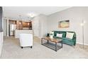 Comfortable living area with a modern green sofa, a side table, and an open layout into the kitchen at 10052 W Ute Pl # 202, Littleton, CO 80127