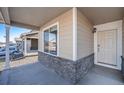 Covered front porch with stone base and a white front door at 47356 Lilac Ave, Bennett, CO 80102