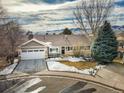 Aerial view of a charming house with a snow-covered yard and mountain backdrop at 2517 S Eldridge Ct, Lakewood, CO 80228
