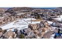 Overhead view of a home nestled within a picturesque landscape, featuring snow-dusted fields and surrounding neighborhood at 16403 River Haven Way, Morrison, CO 80465