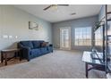 Bright living room features a comfortable blue sofa, ceiling fan and access to the outdoors at 2682 S Cathay Way # 307, Aurora, CO 80013