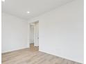 Minimalist bedroom featuring wood-look floors, neutral walls, and a doorway leading to another room at 24780 E 39Th Ave, Aurora, CO 80019