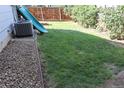 Grassy backyard featuring a slide, lush green lawn, and a well-maintained wooden fence for added privacy at 7988 S Johnson Ct, Littleton, CO 80128