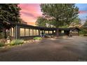 Charming single-story home with a paved driveway, mature trees, and beautifully landscaped front yard at sunset at 29663 Paint Brush Dr, Evergreen, CO 80439