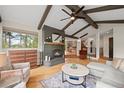 Bright living room boasts vaulted ceilings, exposed beams, hardwood floors, and a cozy fireplace at 29663 Paint Brush Dr, Evergreen, CO 80439
