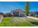 Gray exterior ranch home with stone accents, two-car garage, and landscaped lawn at 42396 Glen Abbey Dr, Elizabeth, CO 80107