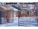 Charming front exterior showcasing an iron gate, a snow covered yard, and the inviting facade of the brick home at 1150 W Caley Ave, Littleton, CO 80120