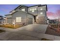 Modern two-story home featuring gray siding, stone accents, and a spacious driveway at twilight at 6863 Oak Canyon Cir, Castle Pines, CO 80108