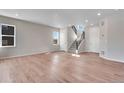 Bright, open-concept living room with sleek hardwood floors, a staircase, and natural light from nearby windows at 6863 Oak Canyon Cir, Castle Pines, CO 80108