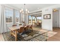Light-filled dining room with views of the yard has modern chandelier, wood table, and floor-to-ceiling windows at 15 Latigo Pl, Littleton, CO 80123