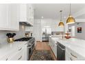 Gourmet kitchen features stainless appliances, white cabinets with gold hardware, and marble backsplash at 15 Latigo Pl, Littleton, CO 80123