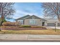 A single story home with a green garage door, beige brick, and a landscaped yard on a bright day at 15123 Xenia St, Thornton, CO 80602