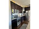 Close-up of a kitchen with stainless steel appliances and dark wood cabinets at 3173 Youngheart Way, Castle Rock, CO 80109