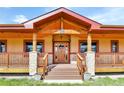 Inviting front porch with stone pillars and a stained wood front door at 5365 Eldridge St, Arvada, CO 80002