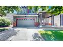 Two car garage on gray home with red accents, landscaped front yard, and covered porch at 19730 E 58Th Pl, Aurora, CO 80019
