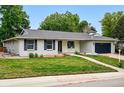 Charming single story house featuring manicured green lawn, rock details, and a two car garage at 6874 S Detroit Cir, Centennial, CO 80122