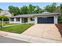 Beautiful exterior showing a well maintained lawn, painted white brick, and two car garage at 6874 S Detroit Cir, Centennial, CO 80122