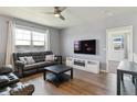 Cozy living room with a black leather couch, modern ceiling fan, and lots of natural light at 4992 Trails Edge Ln, Castle Rock, CO 80104