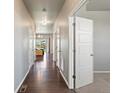 Long hallway with hardwood floors, white doors, and view into dining area with sliding glass doors at 1181 W 170 Th Ave, Broomfield, CO 80023
