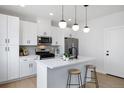 Modern kitchen featuring an island with bar stools, stainless steel appliances, and bright white cabinets at 4018 Upham St, Wheat Ridge, CO 80033