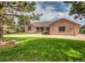 Brick home exterior with a large front yard, mature trees, and a circular driveway at 1660 Old Antlers Way, Monument, CO 80132