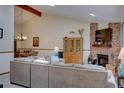 Open-concept living room featuring a brick fireplace, vaulted ceilings with wooden beams, and a dining area at 4231 S Fairplay Cir # A, Aurora, CO 80014