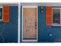 Up-close view of the front door and brick facade with orange shutters and a modern light fixture at 1120 Hartford Dr, Boulder, CO 80305