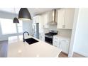 Modern kitchen features stainless steel appliances, an island with a black sink and white cabinetry at 2668 W 68Th Ave, Denver, CO 80221