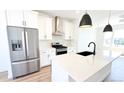 Kitchen boasts stainless steel appliances, a white island with a black sink and modern pendant lighting at 2668 W 68Th Ave, Denver, CO 80221