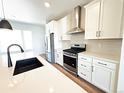 Kitchen featuring stainless steel appliances, white cabinets, and a center island with a black sink at 2668 W 68Th Ave, Denver, CO 80221