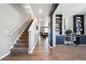 Inviting entryway featuring hardwood floors, staircase, adjacent office space, and a glimpse of the living room at 27130 E Maple Ave, Aurora, CO 80018