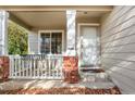 Covered porch with white railing, brick base, and front door at 9441 Wolfe St, Highlands Ranch, CO 80129
