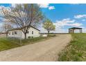 Quaint home with fenced yard, mature trees, and shed or outbuilding in the background at 19810 County Road 1, Berthoud, CO 80513