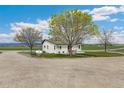 Scenic exterior view of a lovely white home surrounded by mature trees and a gravel driveway at 19810 County Road 1, Berthoud, CO 80513