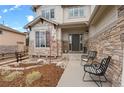 Inviting front porch with seating area and stone accents offer a welcoming entrance to the home at 24355 E Briarwood Ave, Aurora, CO 80016