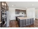 Modern kitchen featuring dark cabinetry, stainless steel appliances, and a large center island with countertop sink at 6214 Long Branch Dr, Parker, CO 80134