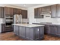 Bright kitchen with stainless appliances, a center island with a quartz countertop, and dark wood-tone cabinetry at 6214 Long Branch Dr, Parker, CO 80134