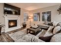 Cozy living room features a fireplace, plush seating, a patterned rug, and large windows at 6894 E 133Rd Pl, Thornton, CO 80602