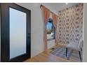 Bright foyer featuring wallpaper, light wood flooring, and a frosted glass door at 6260 Lamar St, Arvada, CO 80003