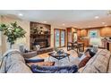 Open-concept living room with stone fireplace, hardwood floors, and views into the kitchen at 26732 Main St, Conifer, CO 80433