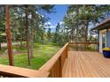 Scenic view from the wooden deck overlooking a lush green lawn, framed by towering trees and a beautiful landscape at 4835 Abo Ln, Monument, CO 80132