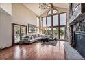 Spacious living room with vaulted ceilings, large windows offering natural light, and a stone fireplace at 2122 Cramner Ct, Evergreen, CO 80439