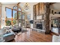 Bright living room boasts a stone fireplace, hardwood floors, and large windows with scenic views at 2122 Cramner Ct, Evergreen, CO 80439