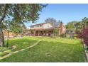 Expansive backyard featuring a large deck, patio, and lush green lawn at 10223 W 77Th Dr, Arvada, CO 80005