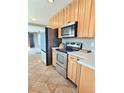 Functional kitchen with stainless steel appliances, natural wood cabinets, and tile flooring at 3493 S Eudora St, Denver, CO 80222