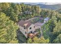 Aerial view of a home with a wraparound deck nestled in a lush forest setting near a mountain range at 5254 Cheyenne Rd, Indian Hills, CO 80454