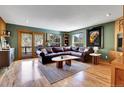 Cozy living room with a leather sectional, hardwood floors, and mountain views from the sliding door and windows at 5254 Cheyenne Rd, Indian Hills, CO 80454