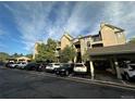 Street-side view of the condo and carports showing a row of parked cars on a sunny day with partly cloudy skies at 7355 S Alkire St # 203, Littleton, CO 80127