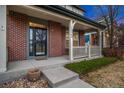 Inviting front porch with brick columns and decorative railings leading to the entry at 13744 W 86Th Dr, Arvada, CO 80005